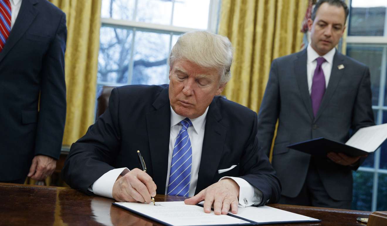 Donald Trump signs the executive order to withdraw the US from the Trans-Pacific Partnership trade pact agreed under the Obama administration. Photo: AP