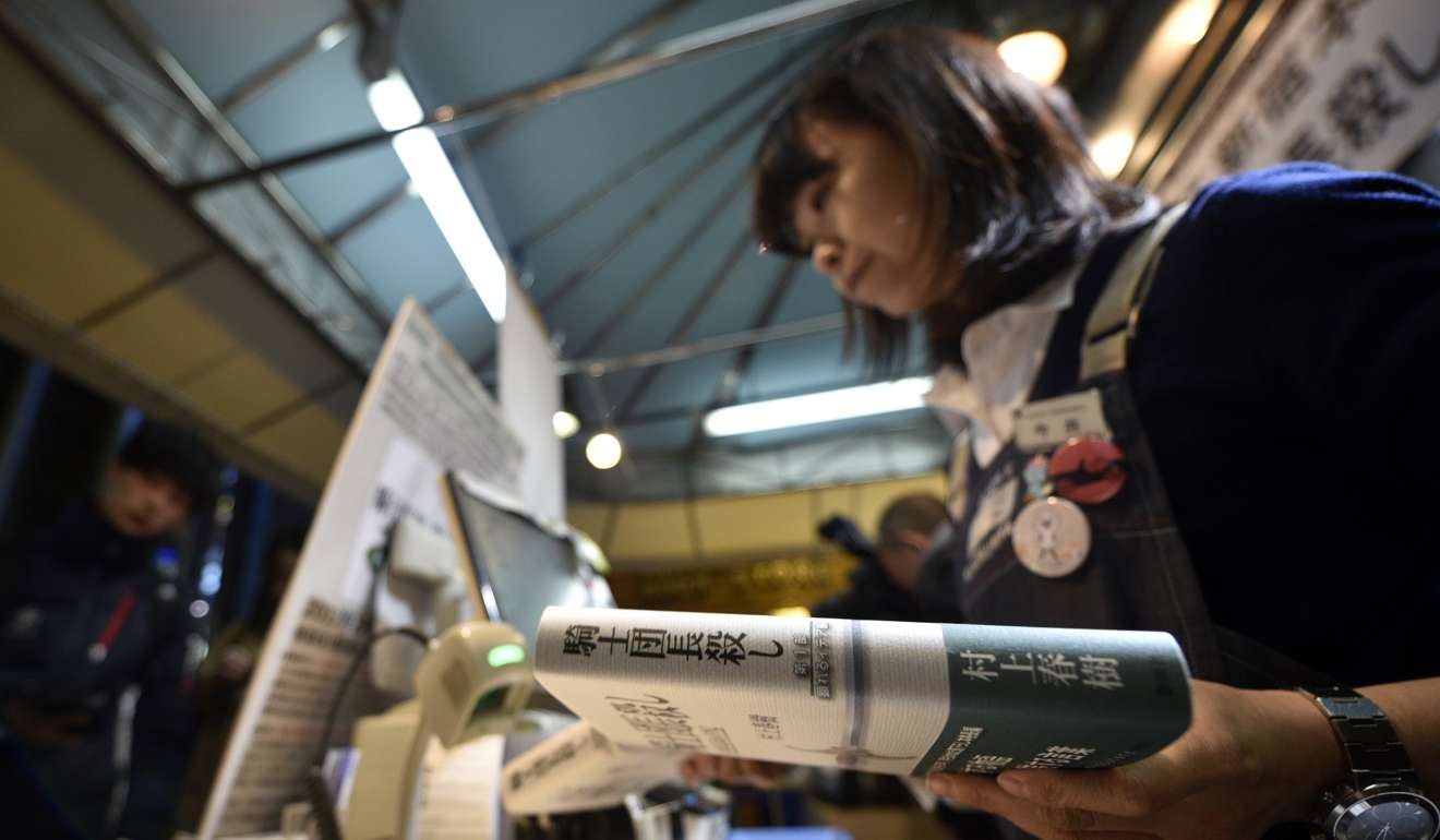 A bookstore employee holds a copy of Japanese best-selling author Haruki Murakami new book 'Kishidancho Goroshi' or 'Killing Commendatore' at Kinokuniya bookstore in Shinjuku district, Tokyo. Photo: EPA