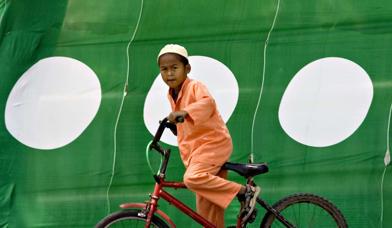 A Muslim child rides past flags belonging to the opposition Pan-Malaysian Islamic Party Terengganu, which has previously approved the use of hudud. Photo: AFP
