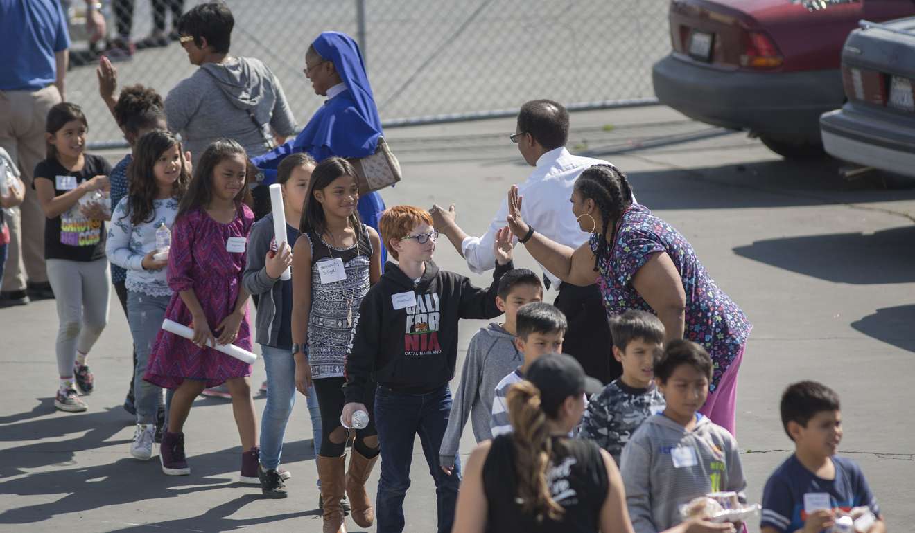 Volunteers encourage North Park Elementary School students with cheers as they arrive to be reunited with parents after a shooting at their school on Monday in San Bernardino, California.Photo: AFP