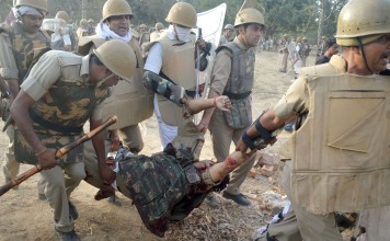 Police carry a colleague injured during clashes with members of a revolutionary sect, said to have encroached a park, in Mathura on Thursday. Photo: AFP