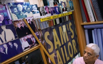 Sam's Tailor boss Manu Melwani points to a photo he has of the late David Bowie visiting the shop. Picture: Jonathan Wong