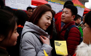 A recruiter hands out a flyer at an employment fair for college graduates in Shijiazhuang, Hebei province. Photo: Reuters