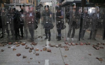 Police stand guard against protesters during the Mong Kok riot. Photo: AP Photo/Vincent Yu