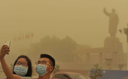 Two residents take a selfie near a statue of Chairman Mao Zedong during a sandstorm in Kashgar, Xinjiang. Photo: Reuters