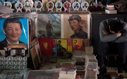A vendor takes a nap next to posters showing Mao Zedong (centre) and Xi Jinping (left) at a market in Beijing. Photo: AFP