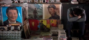 A vendor takes a nap next to posters showing Mao Zedong (centre) and Xi Jinping (left) at a market in Beijing. Photo: AFP