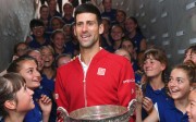 Novak Djokovic poses with his trophy flanked by ball girls. Photo: AFP