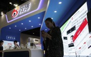 A woman browses her smartphone near a display booth at the Global Mobile Internet Conference in Beijing. Photo: AP A woman browses her smartphone near a display booth at the Global Mobile Internet Conference in Beijing. Photo: AP