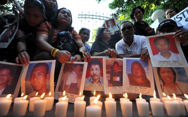 Relatives of the 37 journalists killed in the infamous Maguindanao massacre display portraits of their bereaved loved ones next to lighted candles during a rally in front of the Department of Justice office in Manila on April 21, 2010. Angry relatives of 57 people killed in the Philippines' worst political massacre on April 21 said, they fear the government is protecting a powerful Muslim clan accused of the murders.    AFP PHOTO/TED ALJIBE