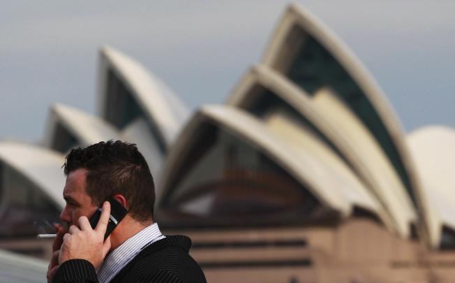 An office worker smokes a cigarette in front of the Sydney Opera House on August 15, 2012. Australia called on the rest of the world to match its tough new anti-tobacco marketing laws after its highest court on Wednesday dismissed a challenge from international cigarette companies in a major test case. REUTERS/Daniel Munoz 
