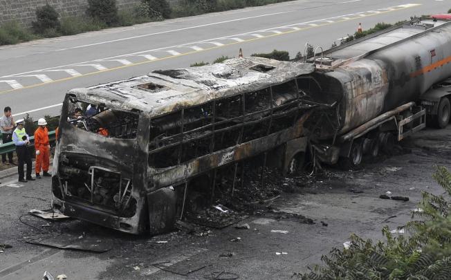 Police and rescuers inspect the charred wrecks of the bus and tanker on the expressway near Yanan , Shaanxi province. Photo: AP