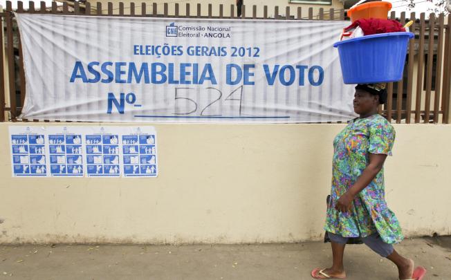 A woman passes by a designated polling station in Luanda. Photo: EPA