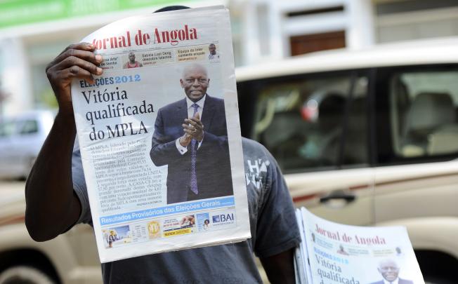 An Angolan newspaper street seller holds up copies of official <i>Jornal de Angola</i> proclaiming the victory of Angolan President Jose Eduardo dos Santos in the streets of Luanda on September 2. Photo: AFP