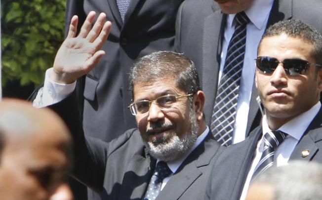 Egyptian President Mohammed Mursi waves to photographers as he leaves the Arab League headquarters in Cairo. Photo: AP