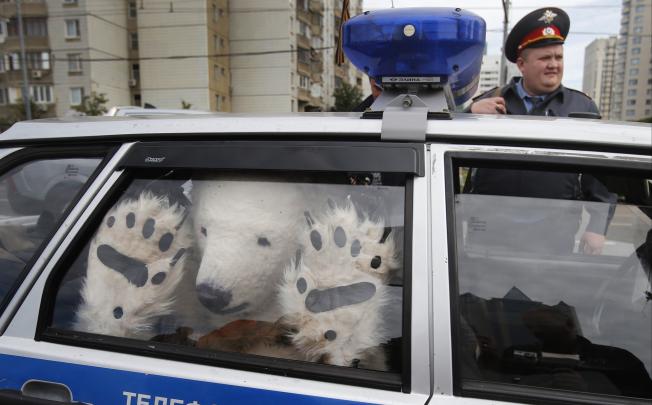 A Greenpeace activist, dressed as a polar bear, sits inside a police car after being detained outside Gazprom's headquarters in Moscow. Photo: AP