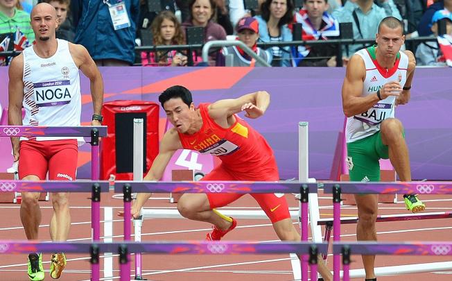 China's Liu Xiang (C) falls while competing in the men's 110m hurdles heats at the Olympic Games in London. Photo: AFP