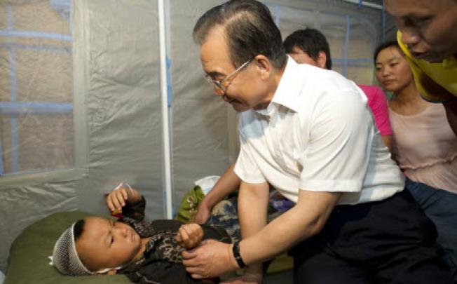 Chinese Premier Wen Jiabao visits an injured child in Yiliang County of Zhaotong, southwest Yunnan Province, on Saturday. Photo: Xinhua