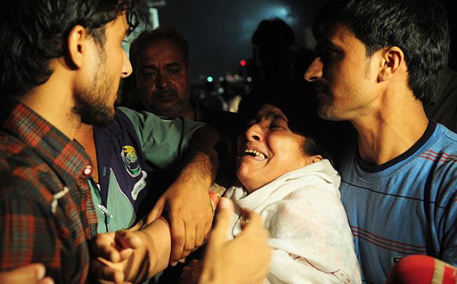 A woman mourns the death of relatives in front of the garment factory. Photo: AFP