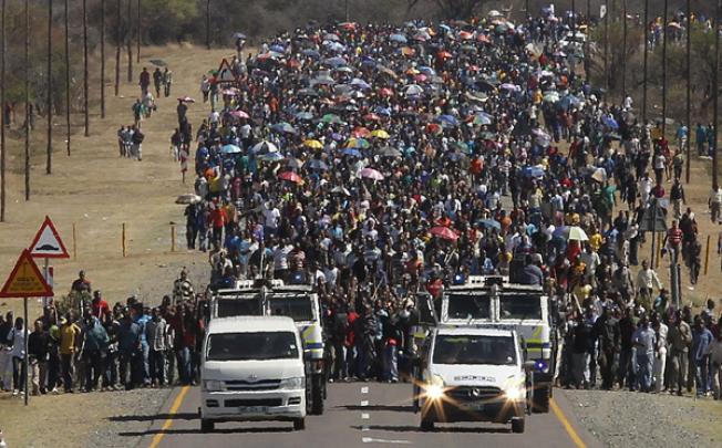 Some of the thousands of striking miners from the Lonmin platinum mine march to the gates of Lonmin mines as part of their mass action in an attempt to get higher wages on Monday. Photo: EPA