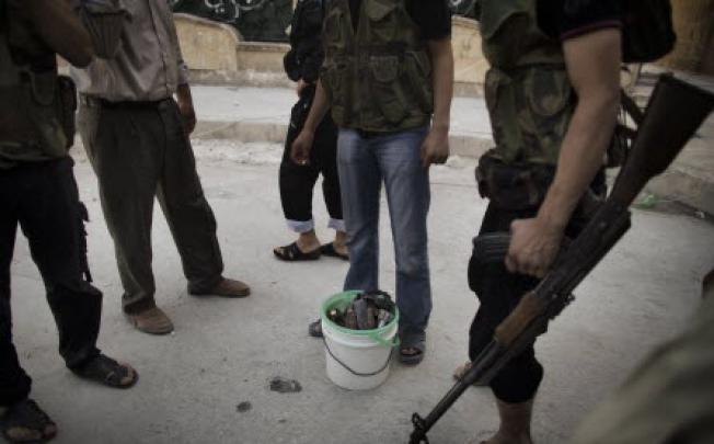 Syrian rebels gather around a bucket of mortars while fighting with scarce ammunition in the Saif al-Dawla neighbourhood of Aleppo on Wednesday. Photo: AFP