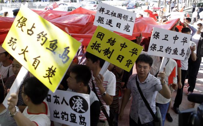 Chinese protesters hold up placards calling for China to unite and defend disputed islands, called Senkaku in Japan and Diaoyu in China, from Japan during a fourth day of protest against Japan, in Beijing, on Friday. Photo: AP