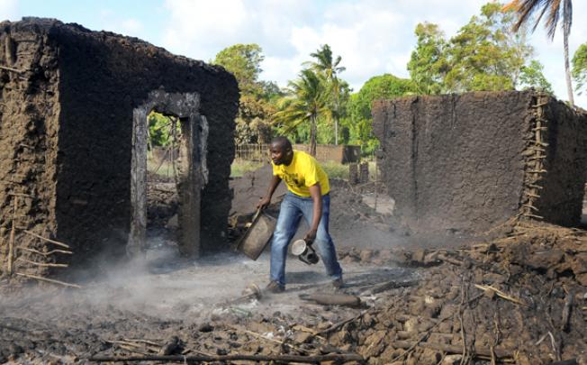 A man picks up belongings from the smoldering remains of a house in the village of Shirikisho, after it was attacked in the Tana River delta. Photo: AP