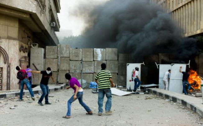 Protesters throw stones over a wall set outside the US embassy in Cairo in Egypt. Photo: Xinhua