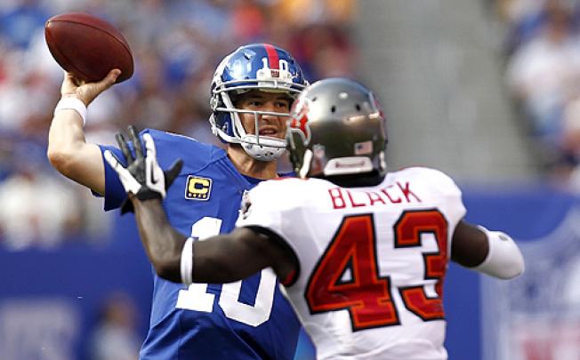 Eli Manning of the Giants (left) passes over Ahmad Black in a game against the Tampa Bay Buccaneers on Sunday. Photo: AFP