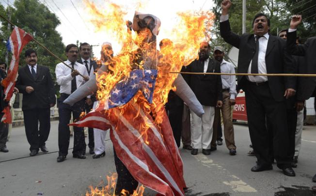 Pakistani lawyers shout slogans as they burn a US flag and an effigy of US President Barack Obama and Florida pastor Terry Jones during a protest in Multan on Monday. Photo: AFP