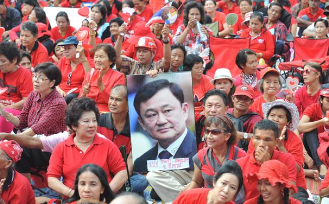 Red Shirt supporters hold a picture of former premier Thaksin Shinawatra during a rally in the central business district of Bangkok on May 19, 2012. Photo: Xinhua