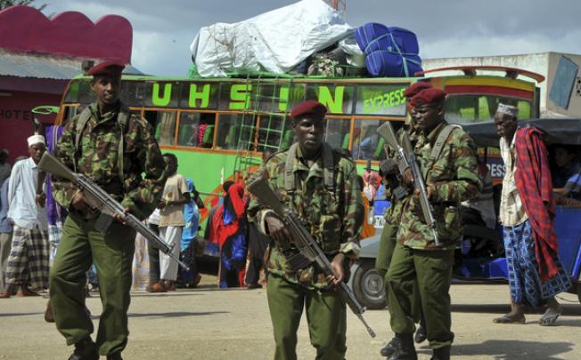 Kenyan police officers patrol in the town of Garsen, as residents pile their belongings onto a bus to leave, in the Tana River area on Saturday. Photo: AP