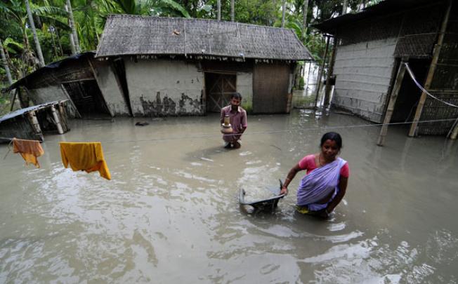 A family move their belongings to a safe place in the flood affected Lasibishnupur village in Kamrup Rural district of Assam state, on Saturday. Photo: EPA
