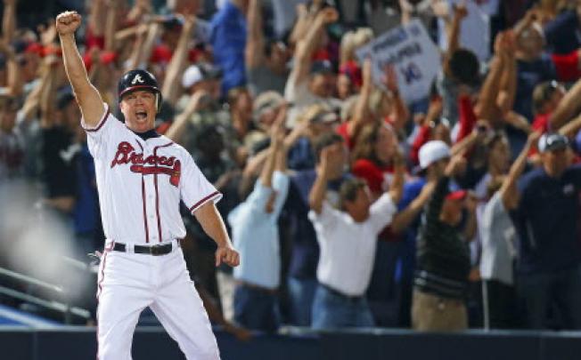 Standing on third base, Atlanta Braves' Chipper Jones reacts along with Braves fans as Freddie Freeman hits a two-run home run to beat the Marlins 4-3 and clinch a wild-card berth for the Braves, at Turner Field in Atlanta on Tuesday. Photo: Associated Press