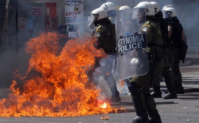 Riot police stand in front of flames caused by a thrown molotov cocktail during violent clashes demonstration in Athens on Wednesday. Photo: EPA