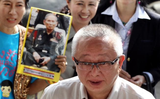 Sondhi Limthongkul passes supporters with one carrying the picture of King Bhumibol Adulyadej at the criminal court in Bangkok on Wednesday. Photo: AP
