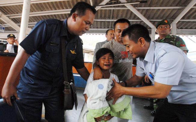 A young survivor of the ferry accident cries as she is escorted by an official at Merak seaport, Banten province on Wednesday. Photo: EPA