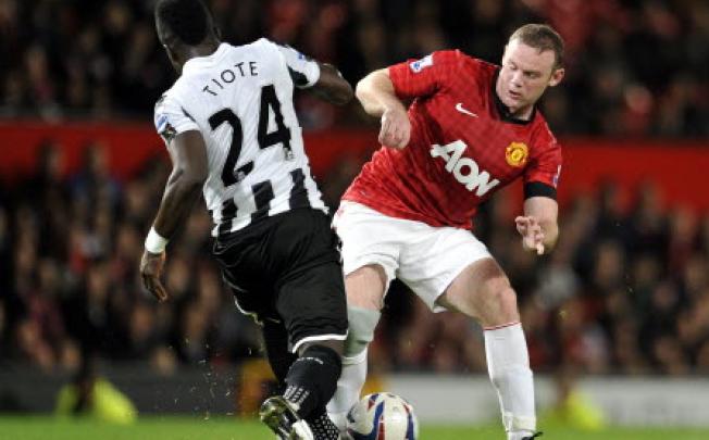 Manchester United's Wayne Rooney (right) is tackled by Newcastle's United's Cheick Tiote (left) during their English League Cup third round match at Old Trafford in Manchester, England on Wednesday. Photo: Associated Press 