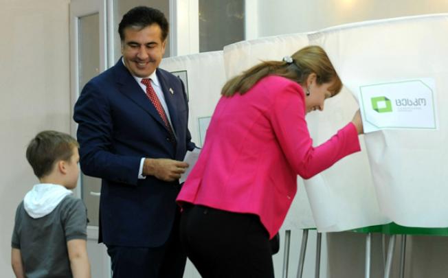 Georgia's President Mikheil Saakashvili looks at his son Nikoloz while his wife, Sandra Roelofs, enters the voting booth at a polling station in Tbilisi. Photo: AFP