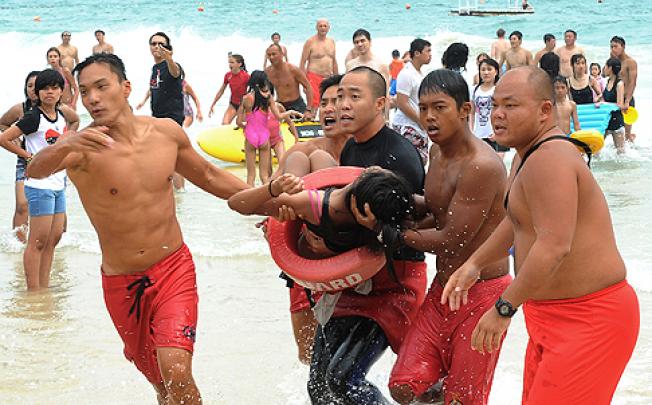 Lifeguards rescue a girl from the ocean after she and her friends were swept away in strong waves at Shek O beach. Photo: SCMP Pictures