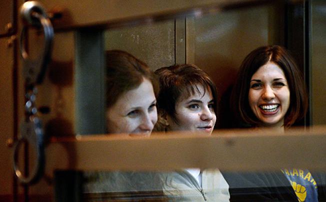 (From left) Yekaterina Samutsevich, Maria Alyokhina and Nadezhda Tolokonnikova sit in a glass-fronted cage during the hearing in a packed Moscow city court on Monday. Photo: AFP