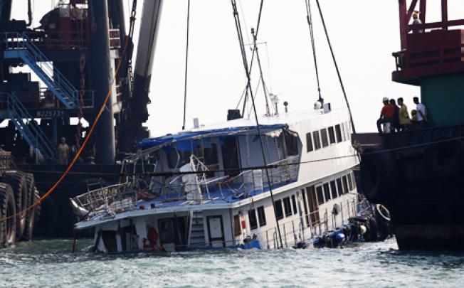 A half-submerged passenger boat is lifted by cranes in waters off Lamma Island on Tuesday. Photo: AP