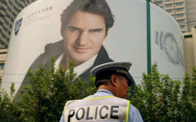 A policeman stands under a giant poster of top-ranked men's tennis player Roger Federer in Shanghai, who will be competing in the Shanghai Masters tennis tournament on Sunday. Photo: AFP