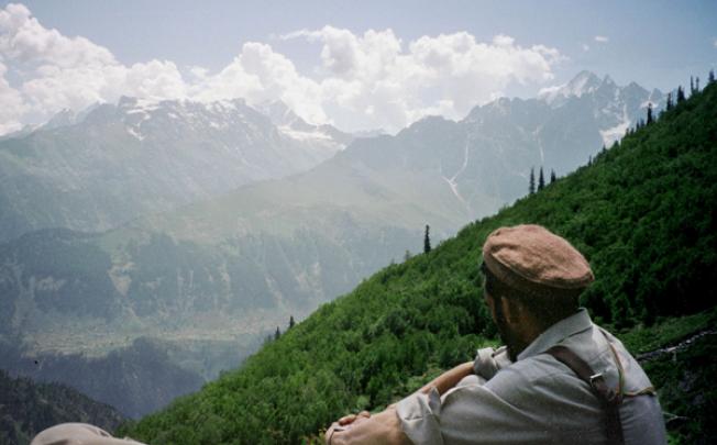 A tourist guide takes a break during a trek in Pakistan's Swat Valley, near the town of Kalam. In the background, the 5,762 metre snow-capped peak of Mankial rises into the clouds. Photo: Reuters