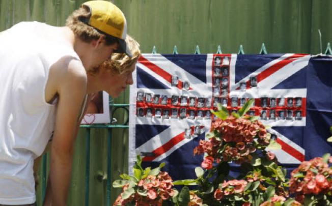 Tourists look at pictures of Bali bombing victims attached to an Australian flag near the 2002 Bali Bombing memorial Monument in Kuta, Bali. Photo: EPA