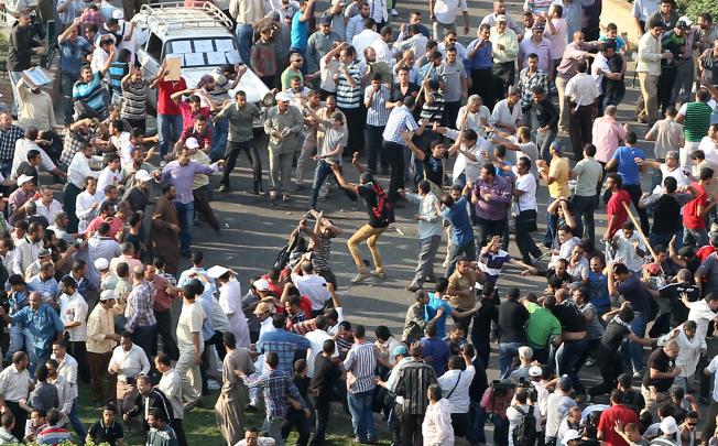 Egyptian Muslim Brotherhood protesters, left, throw stones at opponents of President Mohammed Mursi as they clash in Tahrir Square. Photo: EPA