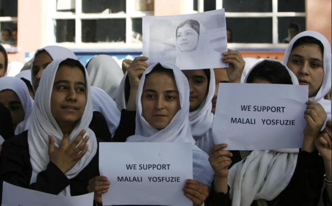 Afghan students hold a portrait of Malala Yousafzai during prayers for her speedy recovery in Herat yesterday. Photo: EPA