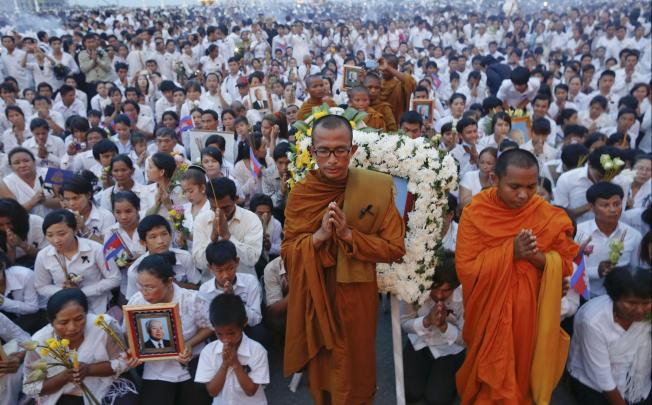Thousands of mourners in white pray at the gates of the Royal Palace in Phnom Penh. Photo: Reuters