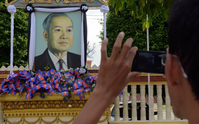 A Cambodian man photographs a portrait of the late former King Norodom Sihanouk near the Royal Palace in Phnom Penh on Thursday. Photo: AFP