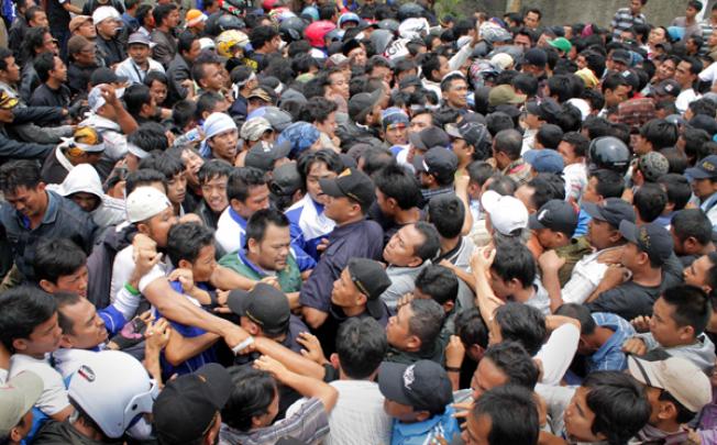 Protestors (left) clash with company security personnel and new employees (right) outside Panarub Dwikarya factory in Tangerang on Thursday. Photo: AFP